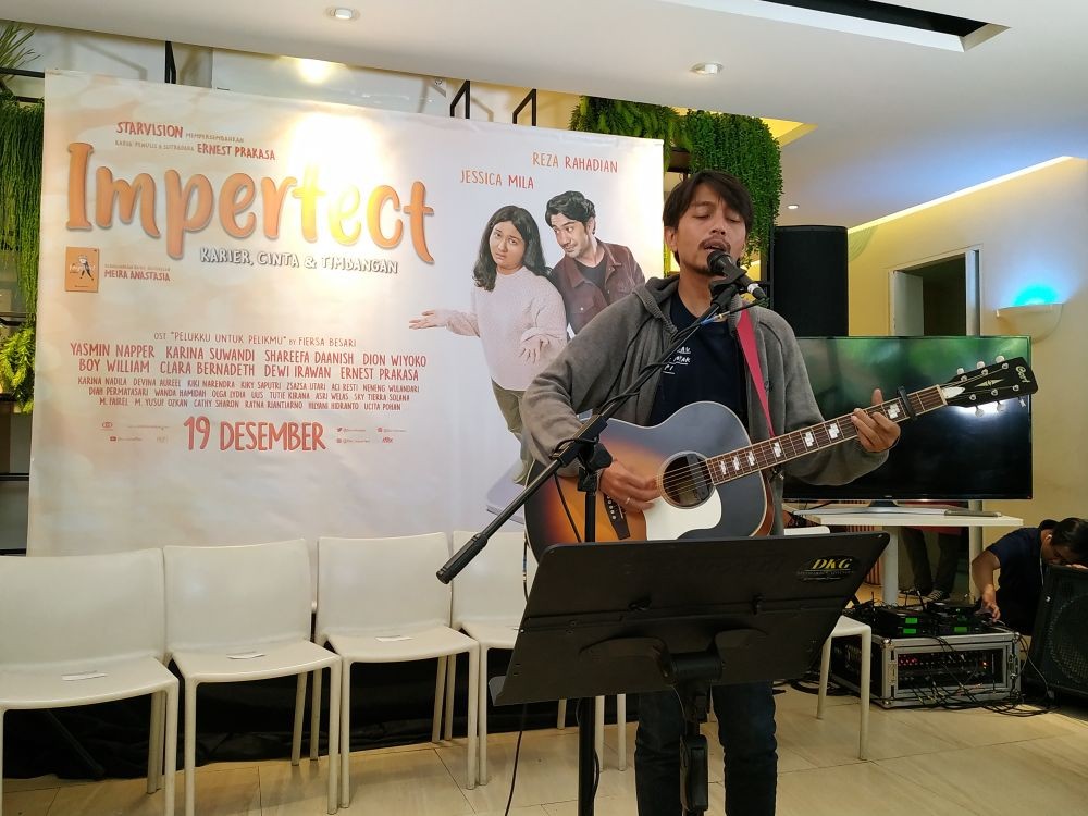 Musisi Fiersa Besari saat tampil di acara perkenalan film Imperfect dengan menggunakan kaus hitam, jaket abu-abu, membawa gitar